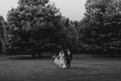 An adventurous bride and groom holding hands and running while they laugh.