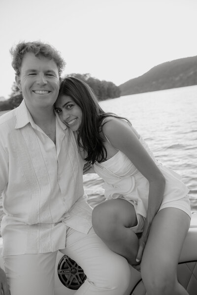 Black and white photo of man and woman smiling together with water in the background