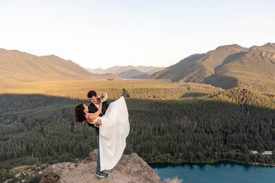 A couple dancing on top of a rocky viewpoint with a mountain valley in the background