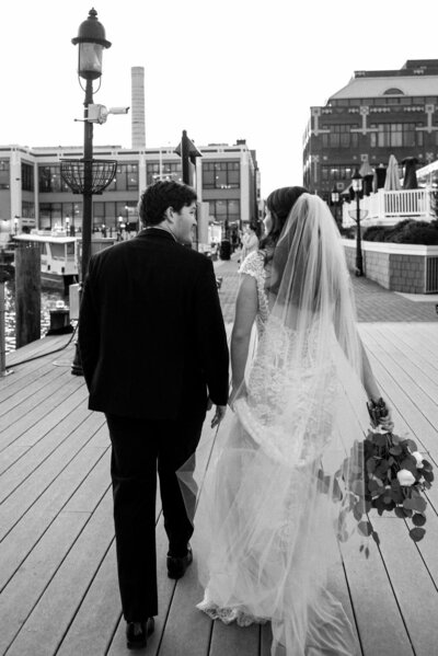 black and white image of bride and groom walking away from camera