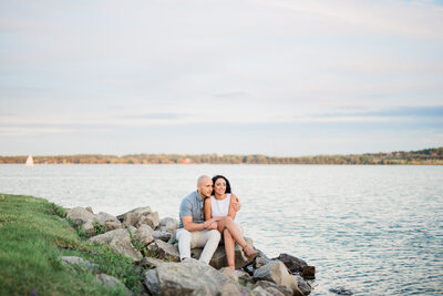 engaged couple sitting by the water