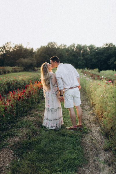 a couple is kissing in a field while wind is sweeping the woman's hair in a Scottsdale field