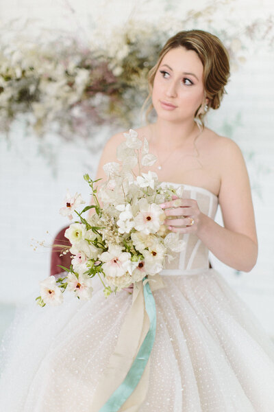 Bride posing for a photo holding a white bouquet of flowers