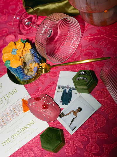 Wedding details with desserts, photos of couple, ring box, champagne glass