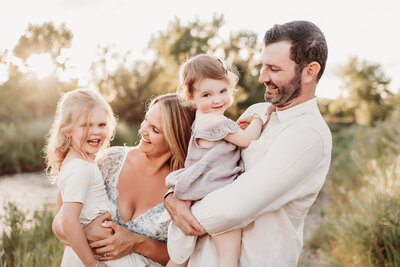 family of four with dad holding youngest and mom holding older girl