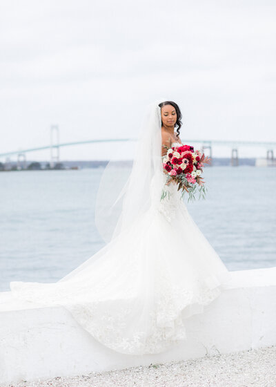 bride standing on white wall at belle mer infront of the pell bridge
