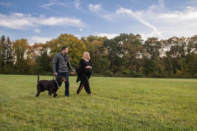 happy pregnant couple walks at Indigo Lake with their dog