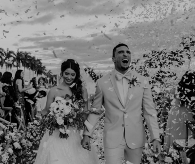 Ceremony moment with bride and groom exiting under a shower of white confetti