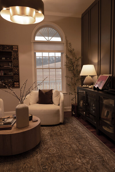 Sitting room with brown rug and white Walmart swivel chair.