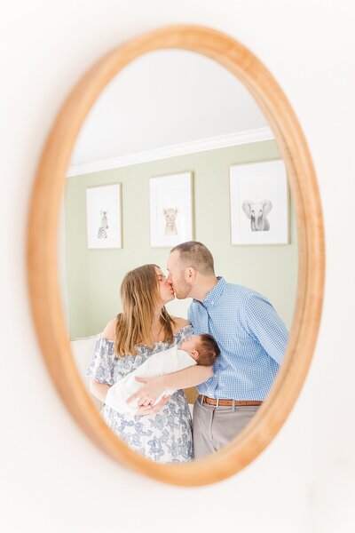 Parents hold baby and kiss during in home newborn photo session with Sara Sniderman Photography in Natick Massachusetts