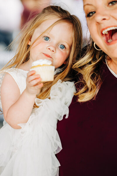 Little flower girl eating a cupcake at wedding reception at Flathead Lake Forevers in Big Arm, MT