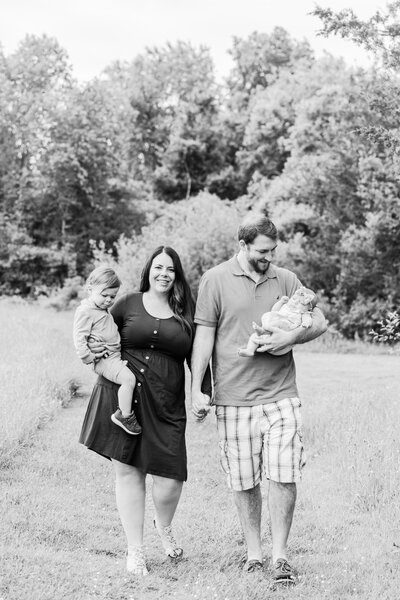 young family walking through a field during their family photos with Corinne Isabelle Photography