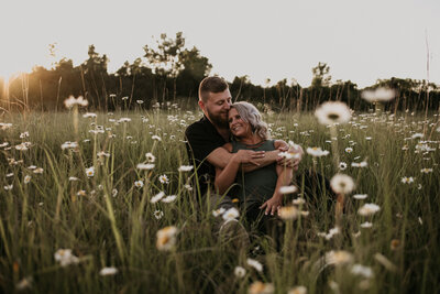 Couple sitting in a field of daisies