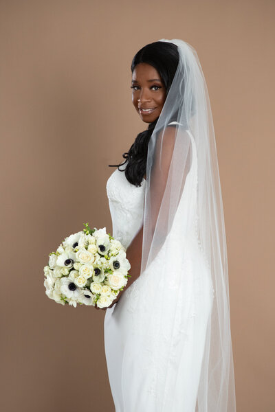 bride wearing a cathedral length veil and holding a white and black bouquet