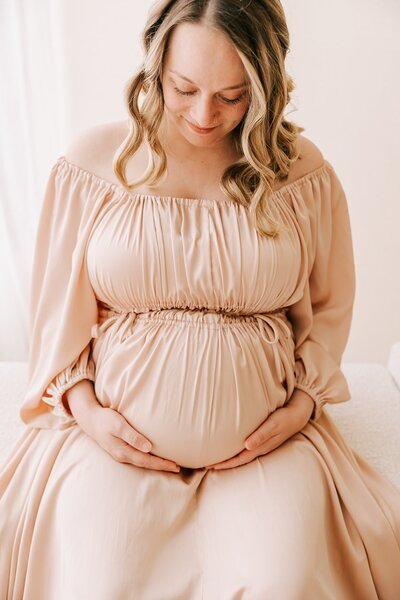expecting mom in tan dress in front of Wahclella Falls, near Portland, Oregon for maternity photography session with Ann Marshall Photography