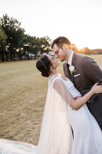 Portrait a bride and groom at sunset, he is dipping her and they are looking at each other romantically