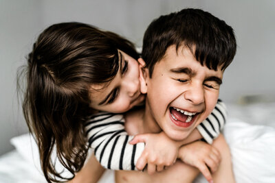 Young brother and sister standing on the beach hugging