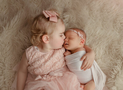 toddler kissing her baby sister