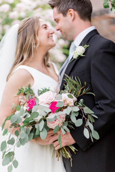 A blush and eucalyptus bouquet being held by a bride and groom