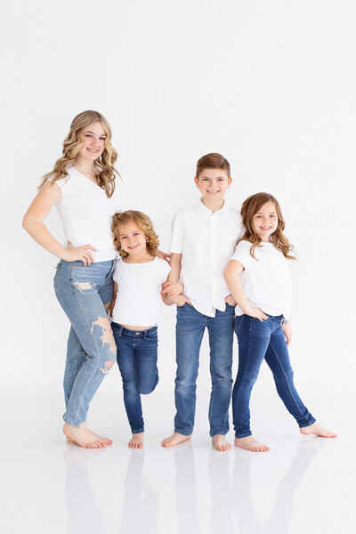 4 siblings standing with their personality showing during photos with Tiffany Hix in Boise studio