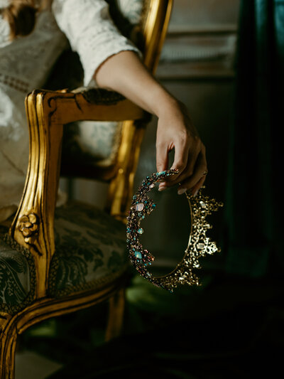 Vermeer Inspired photo shoot hand holding elegant crown with green lighting