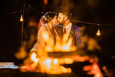 Couple kissing sitting in front of a fire