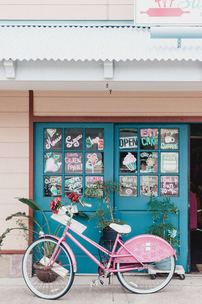 Pink retro bicycle out the front of teal shop doors