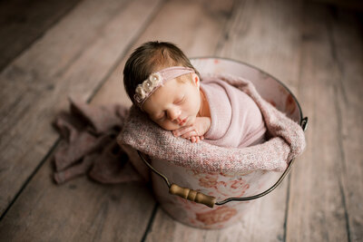 Newborn with headband in bucket