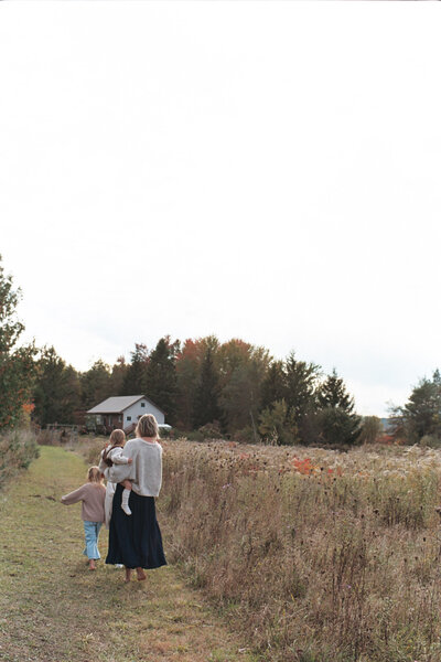 a mother and her daughters walking in a field documented by a  Sudbury Documentary Photographer