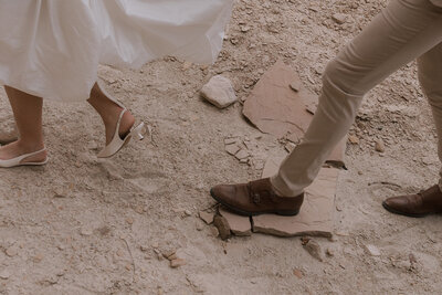 bride and groom hiking in their bridal attire through canyon desert