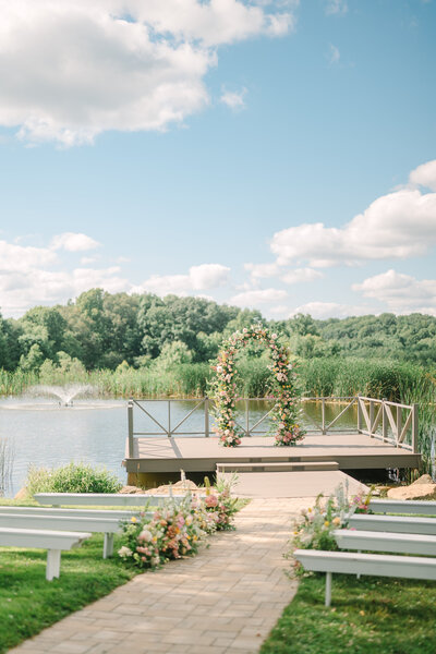 amish white ceremony benches and beautiful peach coral and white wildflowers at the pond on the dock at Willowbrook wedding venue for a wedding ceremony in Pittsburgh