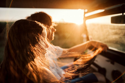 Young couple driving in a car at sunset