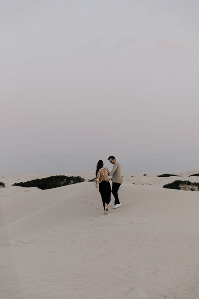 Couple walking on sand dune