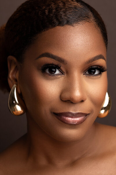 A beautiful studio headshot of a woman smirking at the camera.