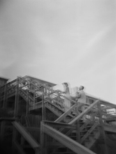 Hazy black and white film photo of family walking up beach boardwalk steps