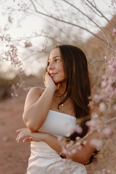 College grad looking off while standing near pink flowers