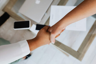 two women in business suits shaking hands 