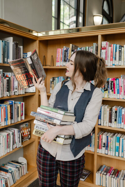 Girl with stack of books in a library