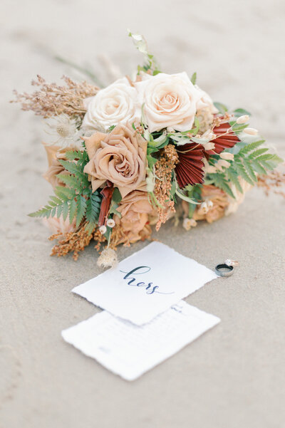 bouquet of roses on the beach  with wedding vows and rings