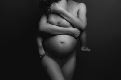 Black and white expectant mother and child sitting on belly