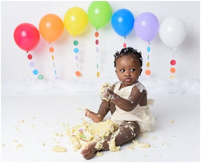A girl's cake smash cake smash session capturing her adorable expressions and messy cake-covered face.