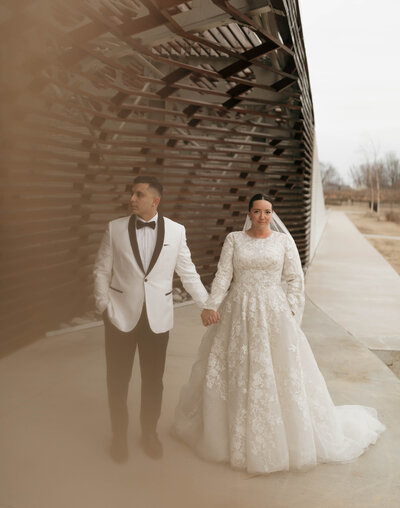 Bride and groom's wedding portrait as they hold hands