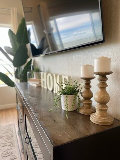 decor below a tv with candles plant and home sign