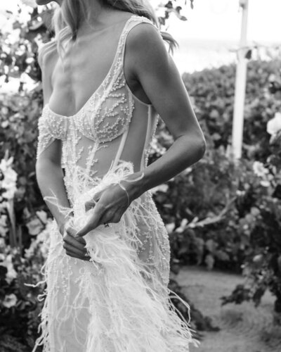 black and white image bride wearing beaded wedding dress with feathers