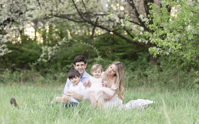 family sitting in grass together photo session.