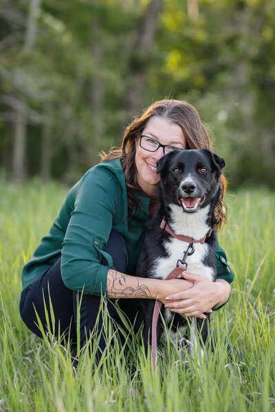 Calgary woman hugging her golden retriever in an Alberta wildflower field with mountains in the distance.