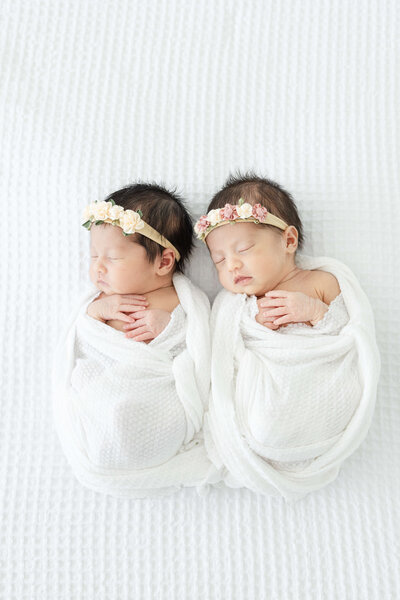 two newborns wrapped up next to eachother
