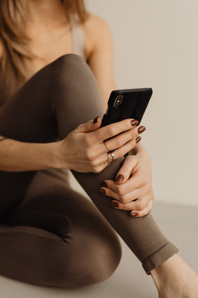 kaboompics_young-adult-woman-yoga-mat-brown-leggings-exercise-outfit-cell-phone-mobile-iphone-28705