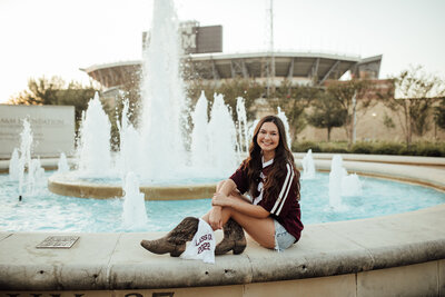 Senior girl smiles in front of water fountain