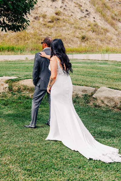 Bride tapping father's shoulder during wedding first look